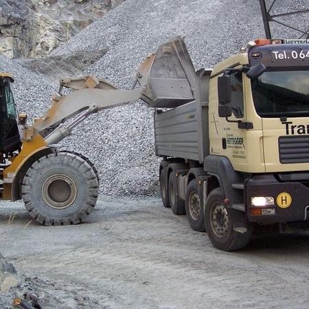 Radlader belädt LKW mit Schotter auf Baustelle