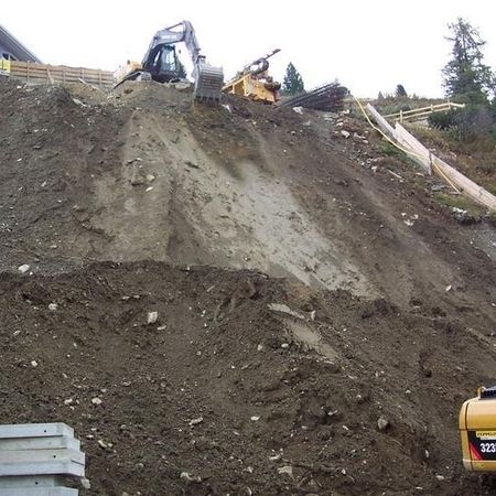Erdarbeiten mit Bagger und Maschinen an einem Hang